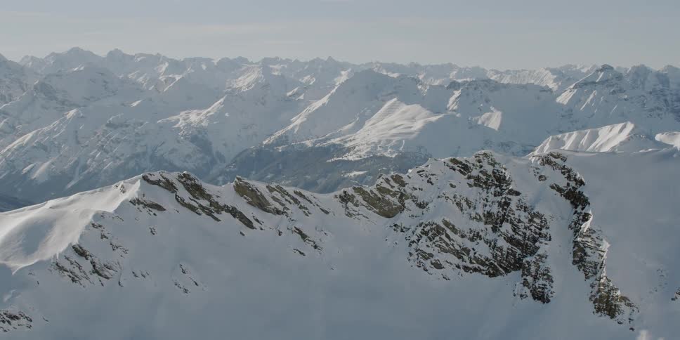 Snow is covering the slopes of a mountain range during the day