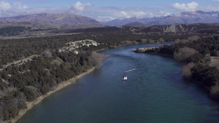Helicopter flies over a long lake