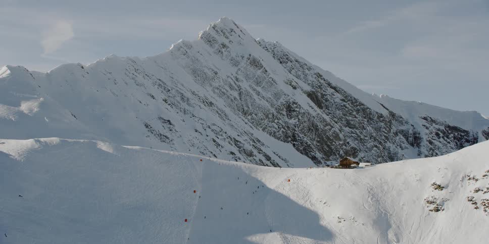 A cabin sits on a snowy mountain ridge