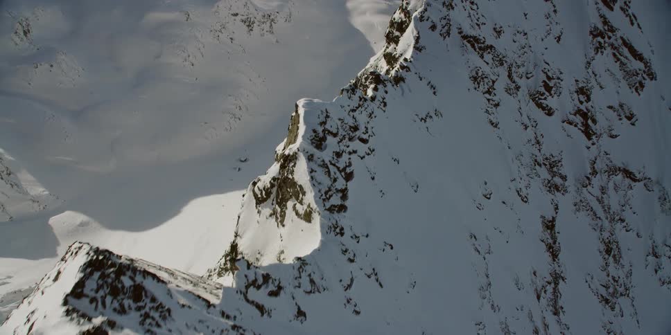 Snow is covering the peaks of a mountain range during the day