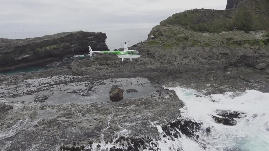Helicopter flying along cliffs and ocean