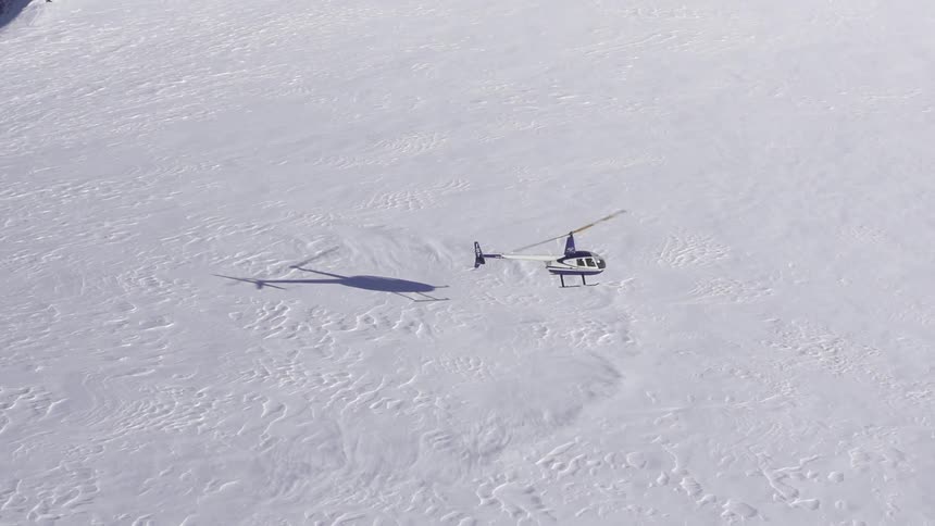 A helicopter hovers over a snowy field