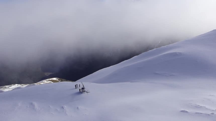 Helicopter and people on top of a snowy mountain
