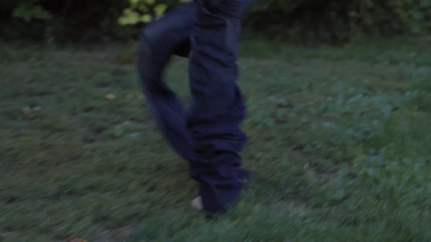 A person hopping on one foot trying to get their jeans on