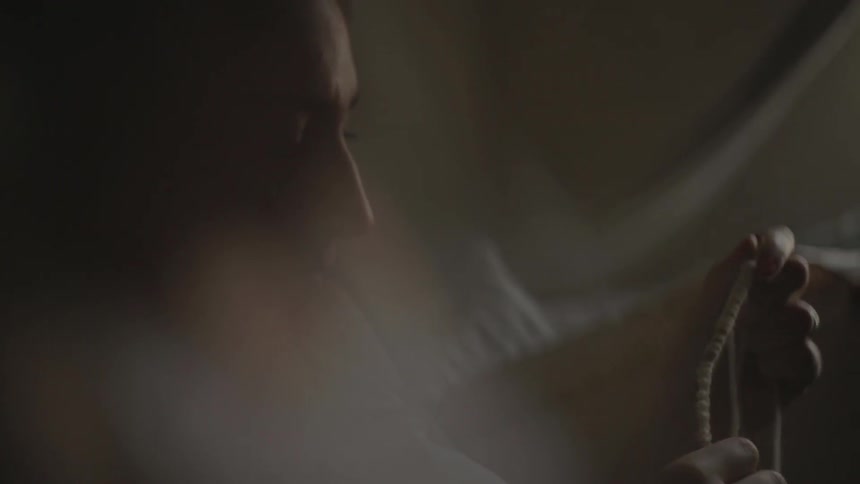 Woman sitting in bed plays with a necklace