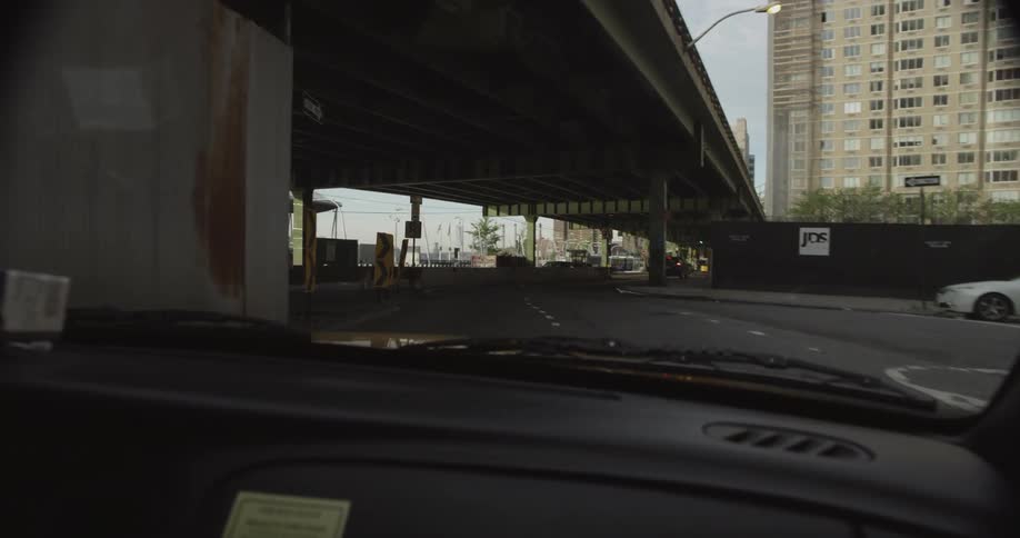 Vehicles driving down a road with buildings around