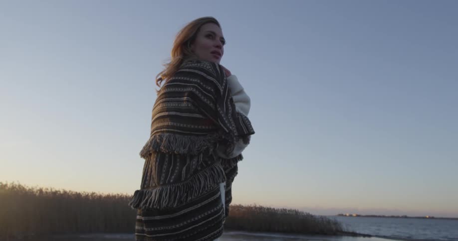 Woman stands by the shore as the sun rises