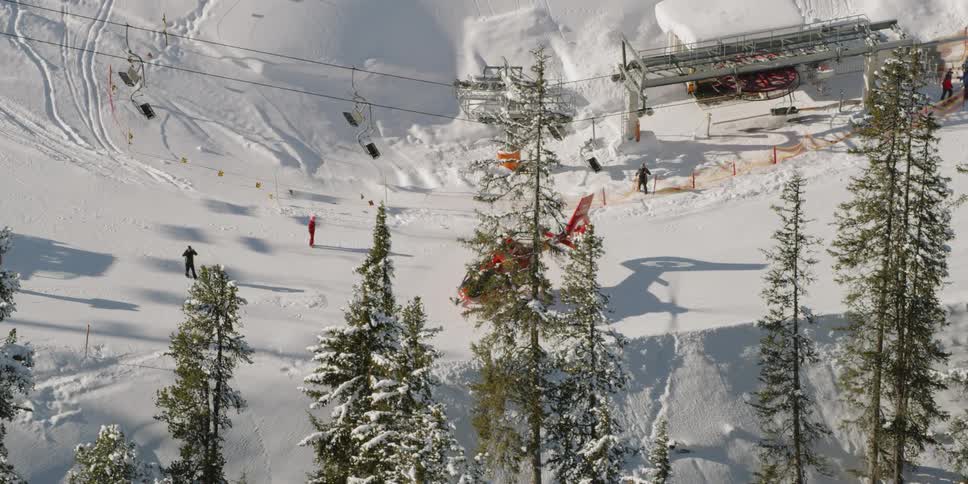 A red helicopter spins its rotor on the top of the mountain