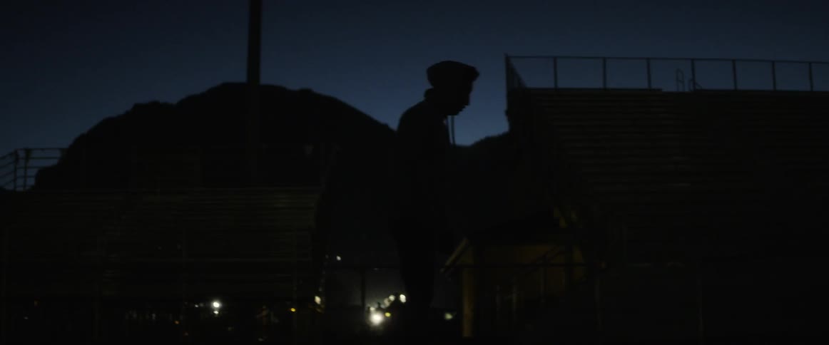 A man stretches by the bleachers