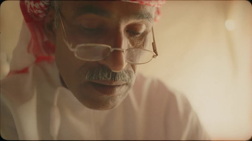 An arab man is sitting inside and reading something in daylight