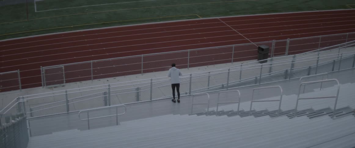 Man leans on a fence then turns and runs up the steps