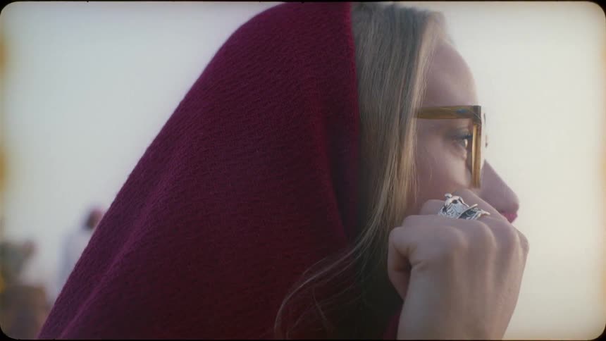 A woman moves the red scarf from her face