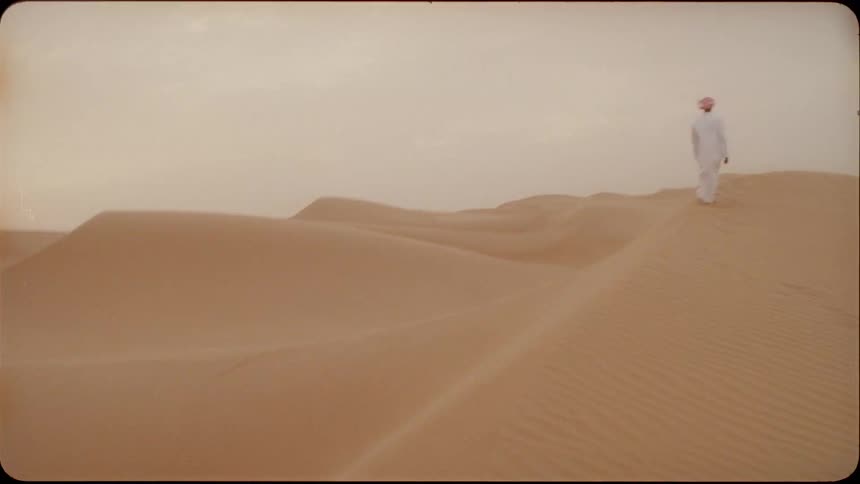 A man walks on the ridge of a sand dune in the desert