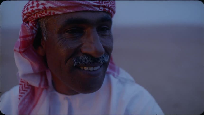 Man wearing a turban smiles as he looks to his left