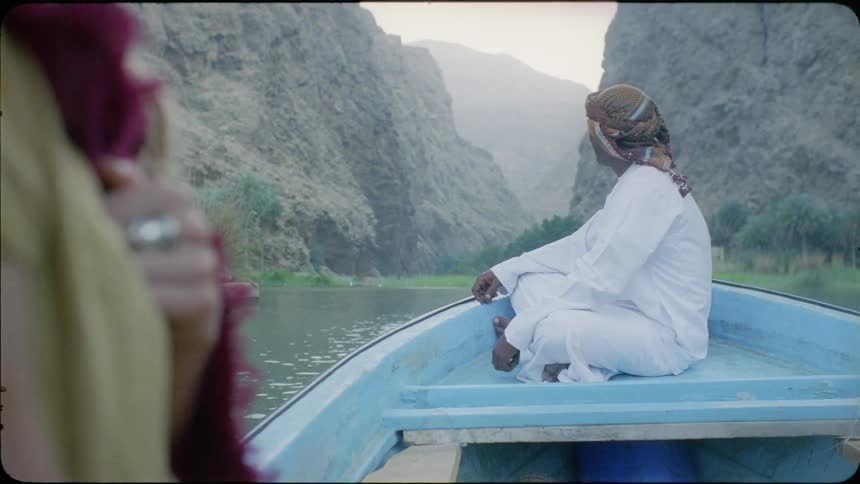 Man smiles at person on boat as they float along a river