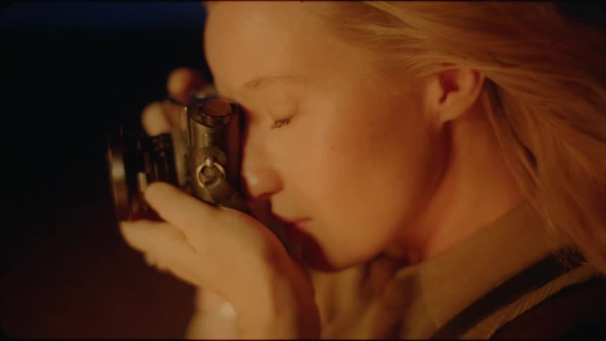 A woman holds up a camera and takes a photo at night