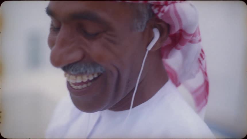 Man in turban with earbuds smiles and nods