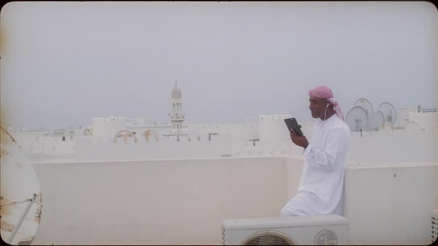 Man wearing a turban laughs as he looks at his cellphone