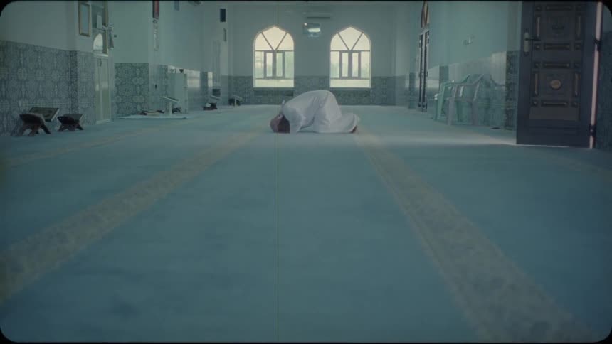 A praying man touches his head to the floor then rises