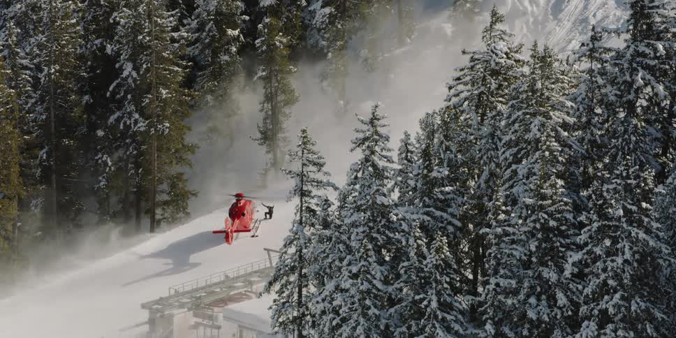 A helicopters rotor sprays snow off the mountain