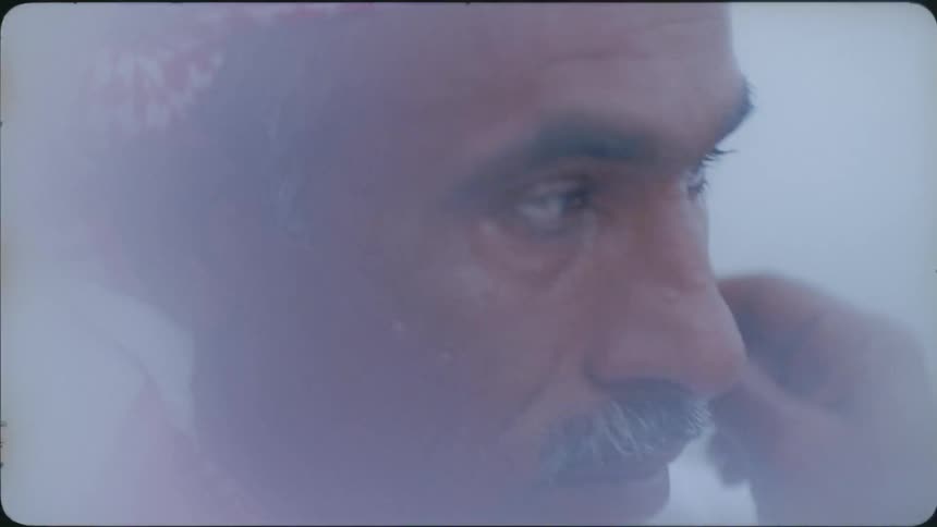 A man shaves his face by the water