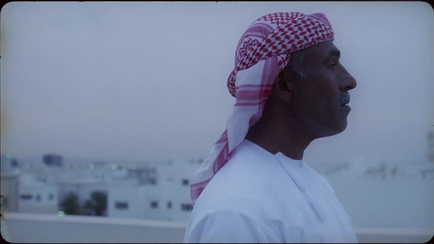 A man stands on a rooftop overlooking a city