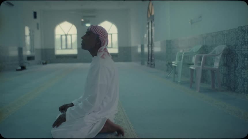 Man kneels in a large room as he looks around