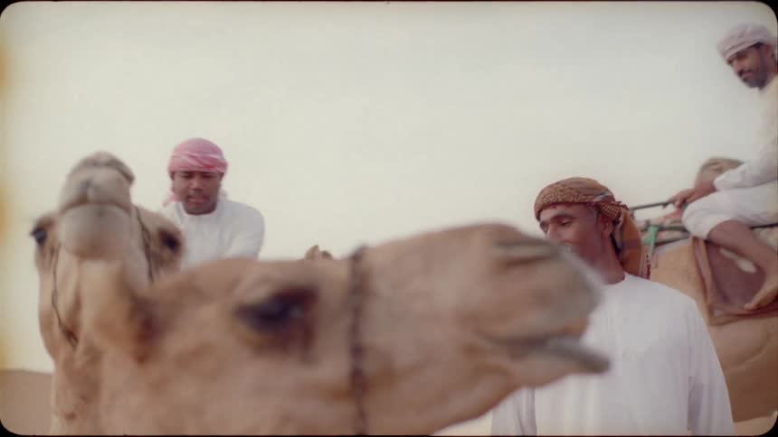 A man mounts a camel in the desert