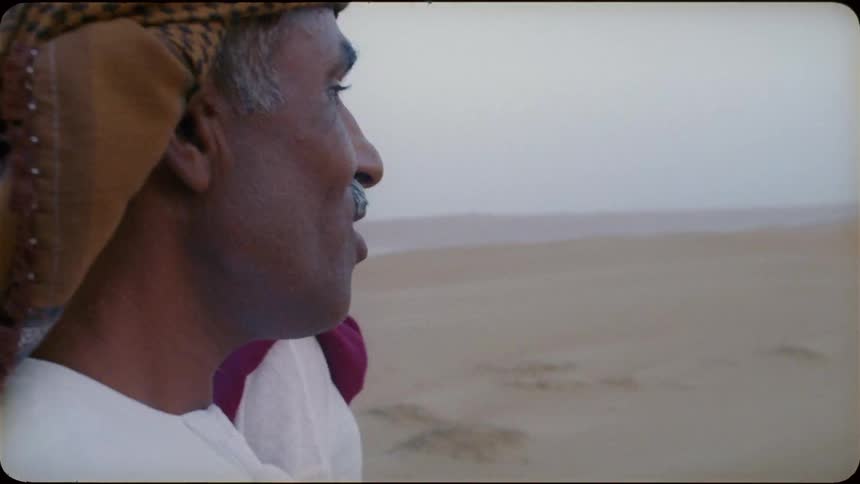 Man and woman talk as they walk on the sand