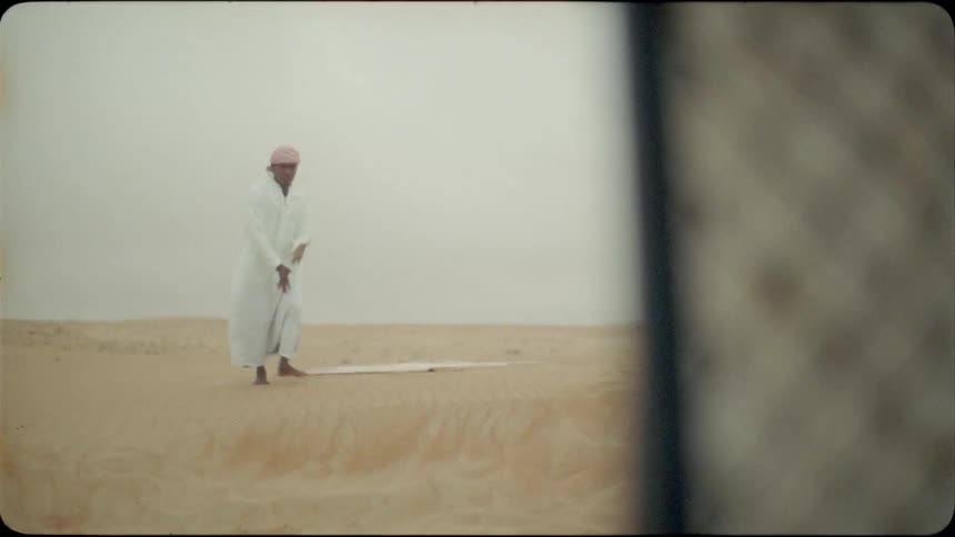 Man arranges a towel on the sand then walks away