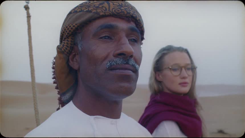 Woman wearing glasses stands near a man wearing a turban