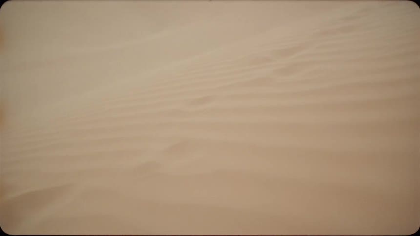 The wind drifts sand across the desert