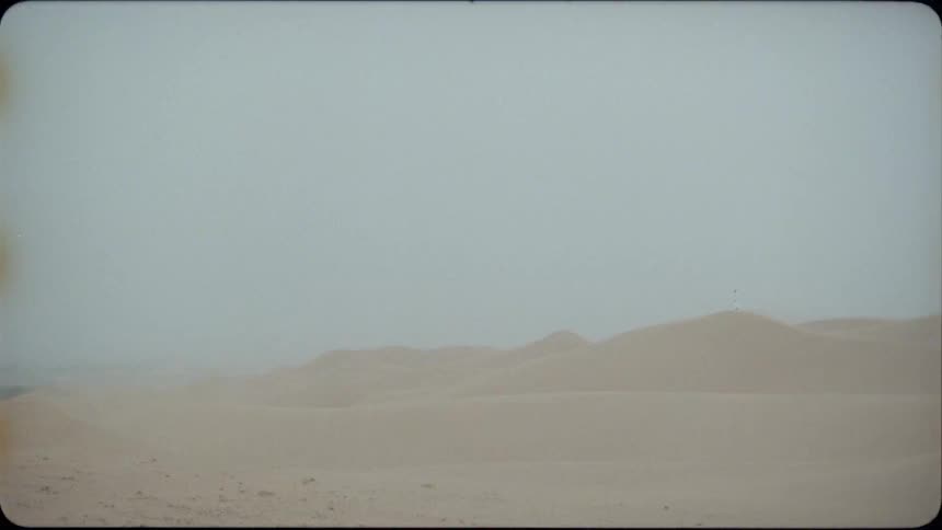 Sand blows in the desert under a blue sky