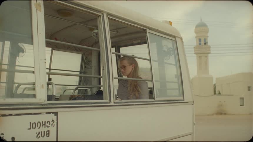 A blond haired woman sits in the back of a van