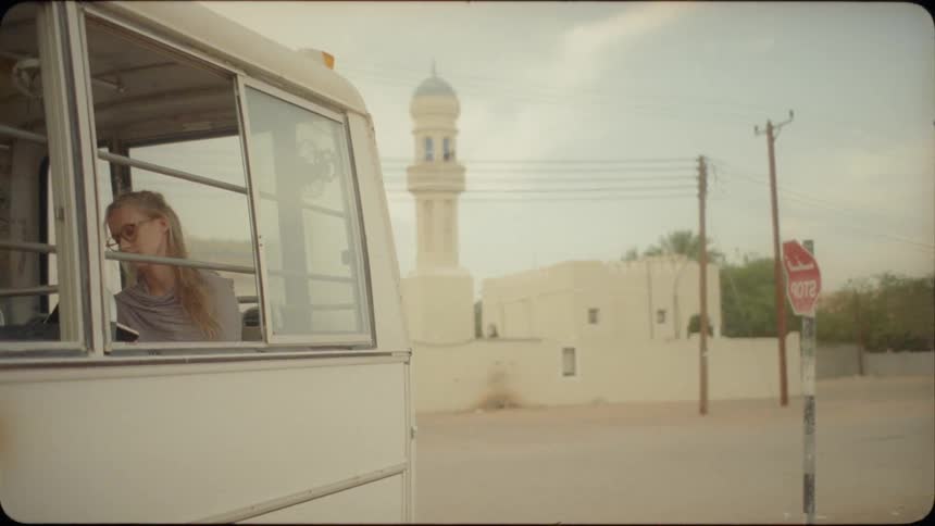 Woman sits on a small white bus in a foreign city