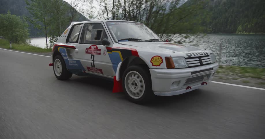 A car with race paint and logos travels on a coastal road