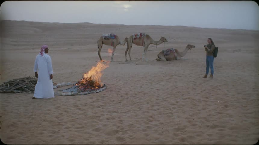A woman is photographing a man by the fire