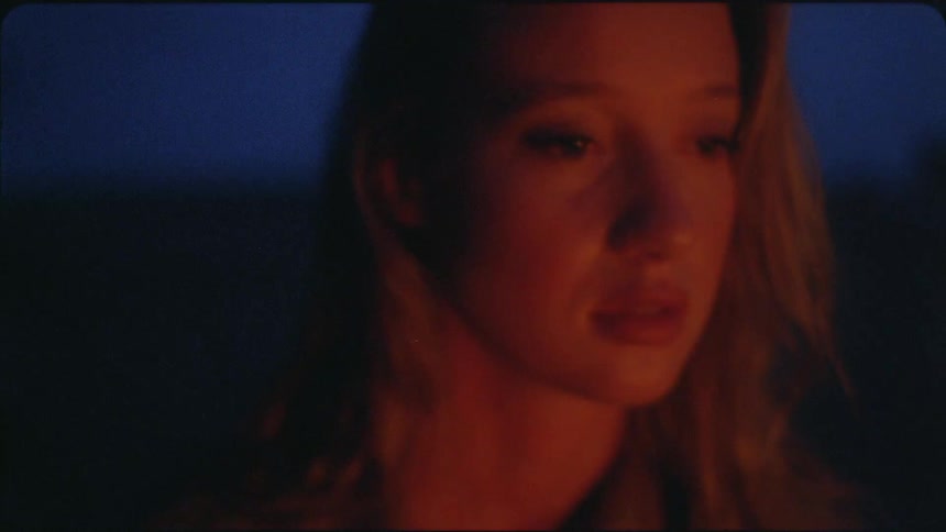 A woman's face is lit by campfire at night