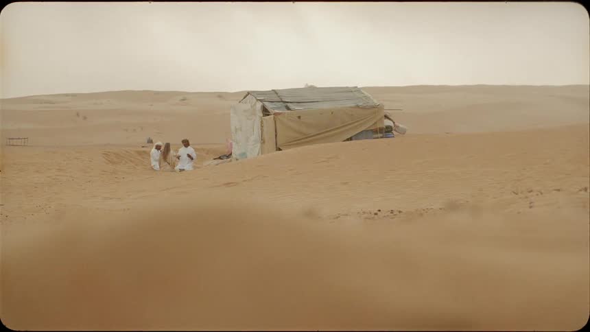 People sit by the tent in the desert
