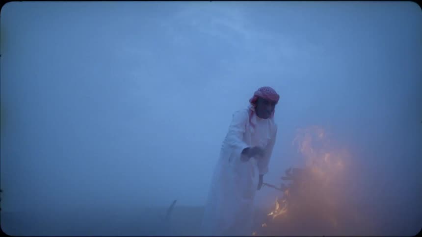 Man tosses sticks onto a bonfire