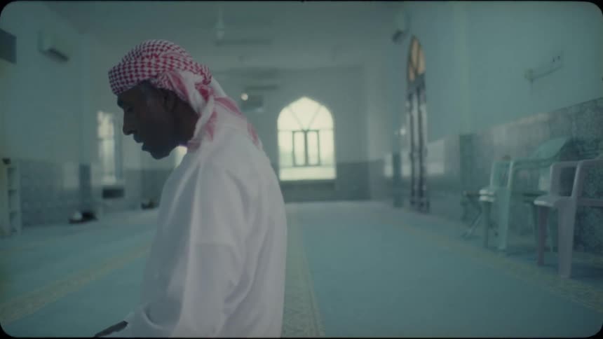 Man wearing head wrap is kneeling on floor of church and praying
