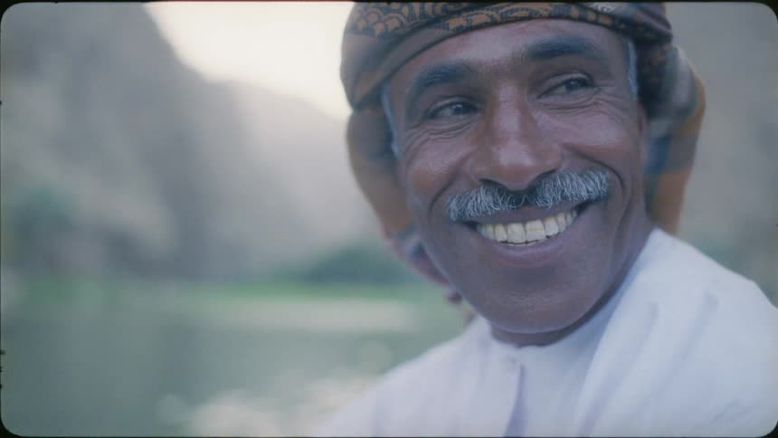 An arab man turns his head and laughs
