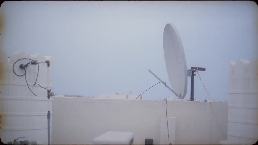 Satellite dish sits on top of a building under a blue sky