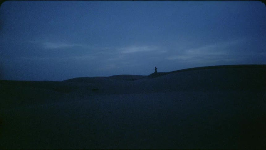 Man runs across the desert under a cloudy sky