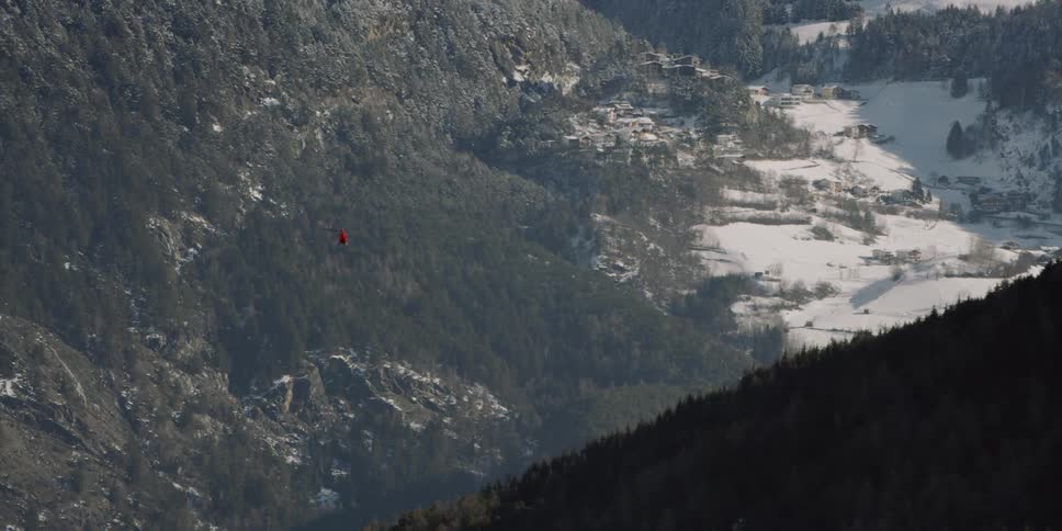 A red helicopter flies between two mountains