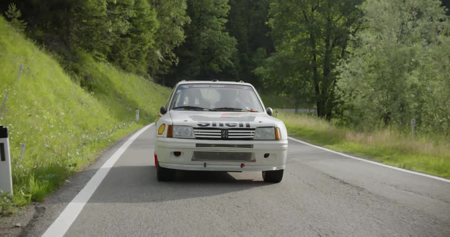 White vehicle drives on a winding country road on a sunny day
