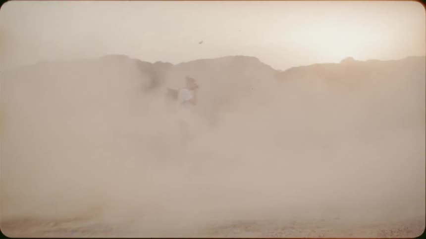 Man records a white vehicle driving through the dust