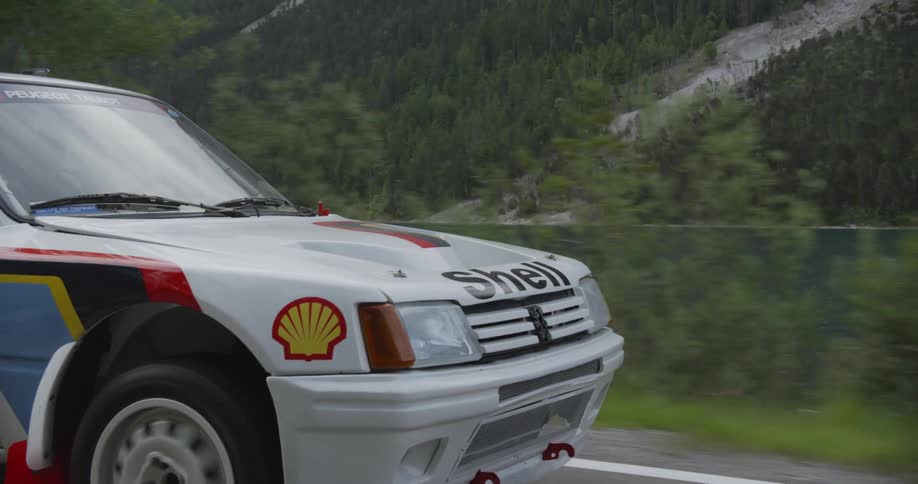 The vehicle is driving down the road by the mountain