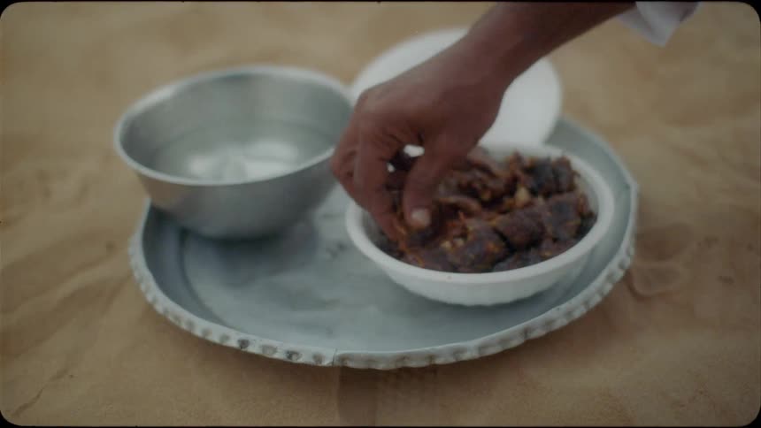 A person grabs a handful of food from the bowl