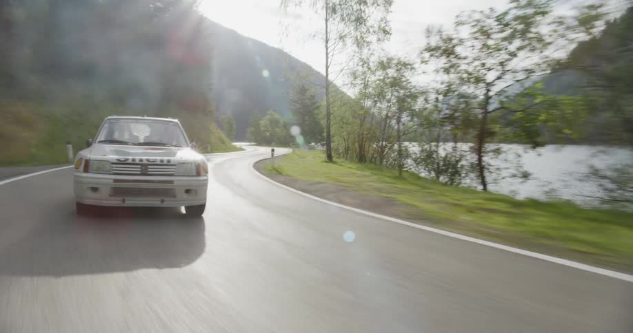 White vehicle drives on a winding country road